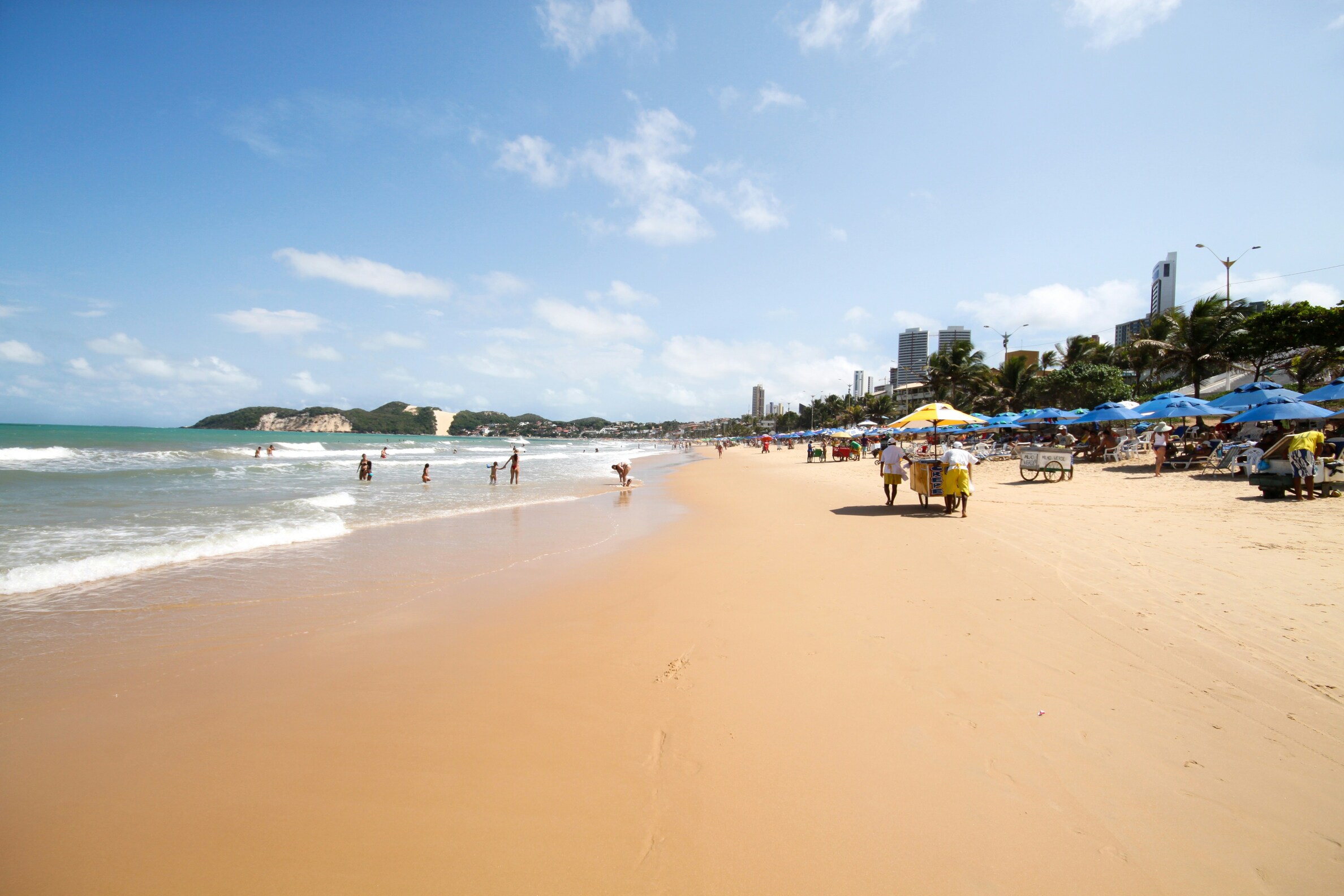 Praia em Natal com faixa de areia, mar e cenário urbano ao fundo